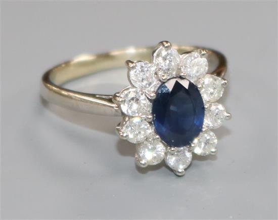 A modern 18ct white gold, sapphire and diamond oval flower head cluster ring, size R/S.